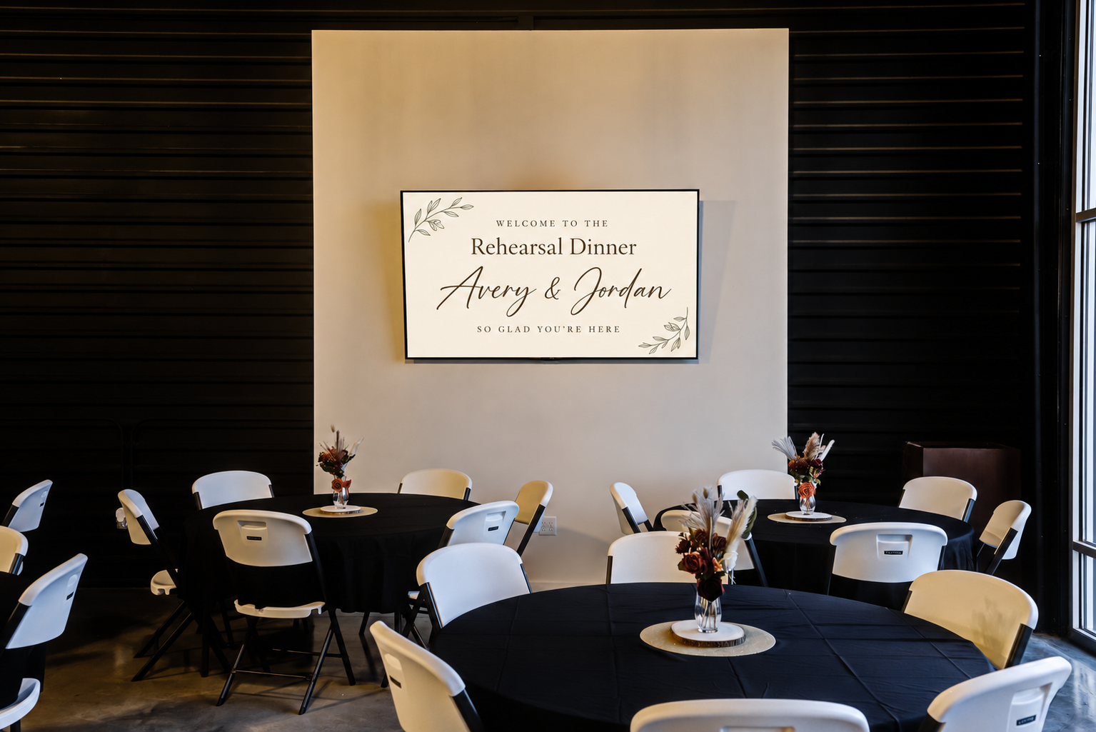 South Hall’s wall-mounted TV showing a personalized rehearsal dinner background for fictional couple Avery and Jordan