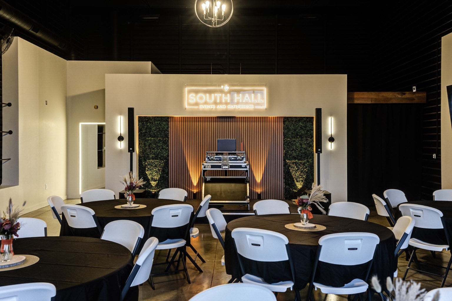 South Hall with round tables, white chairs, warm lighting and its signature stage